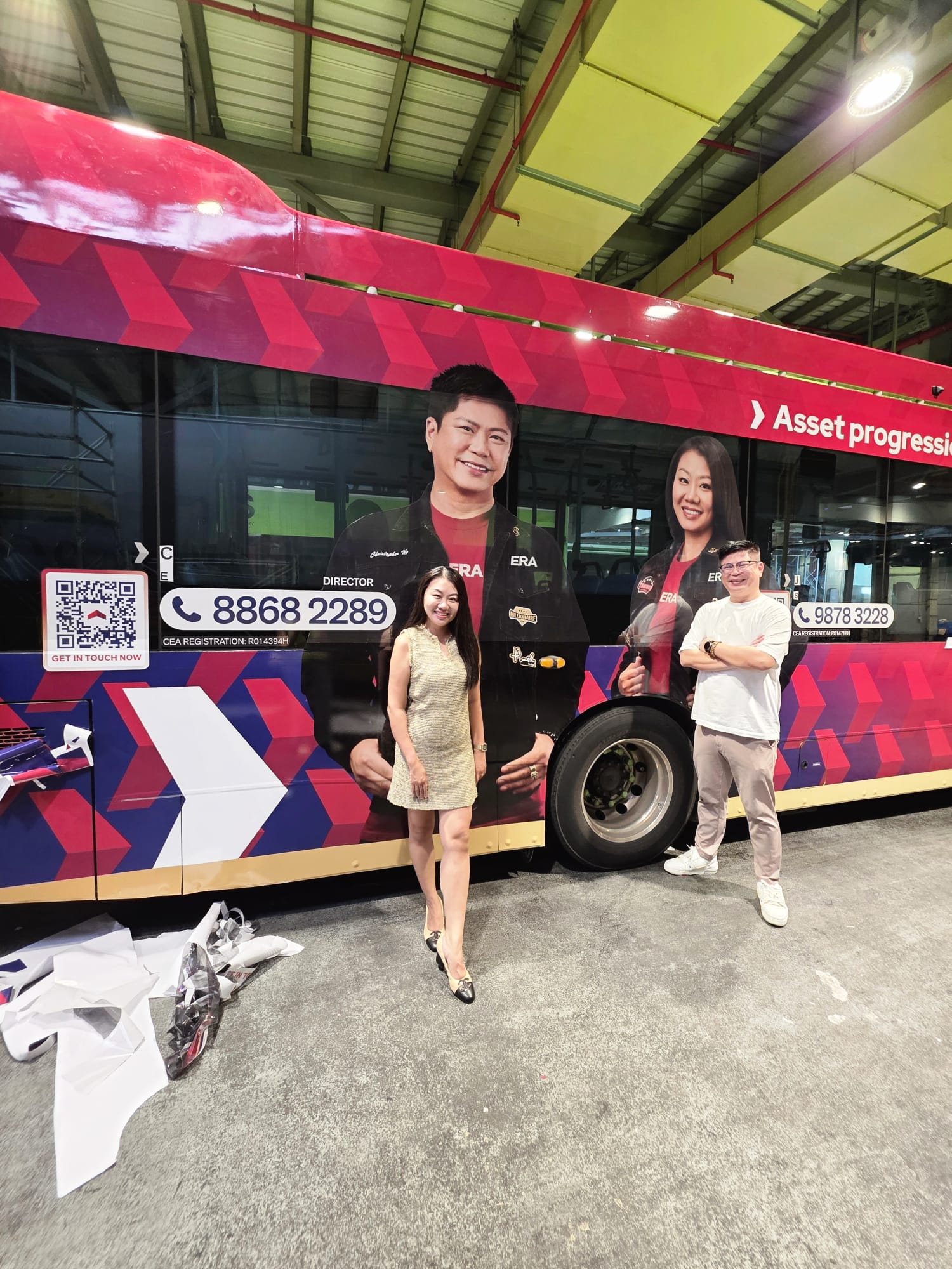 Christopher Ng and Jasmine Chan beside the side panel of the ERA Asset Progression bus wrap